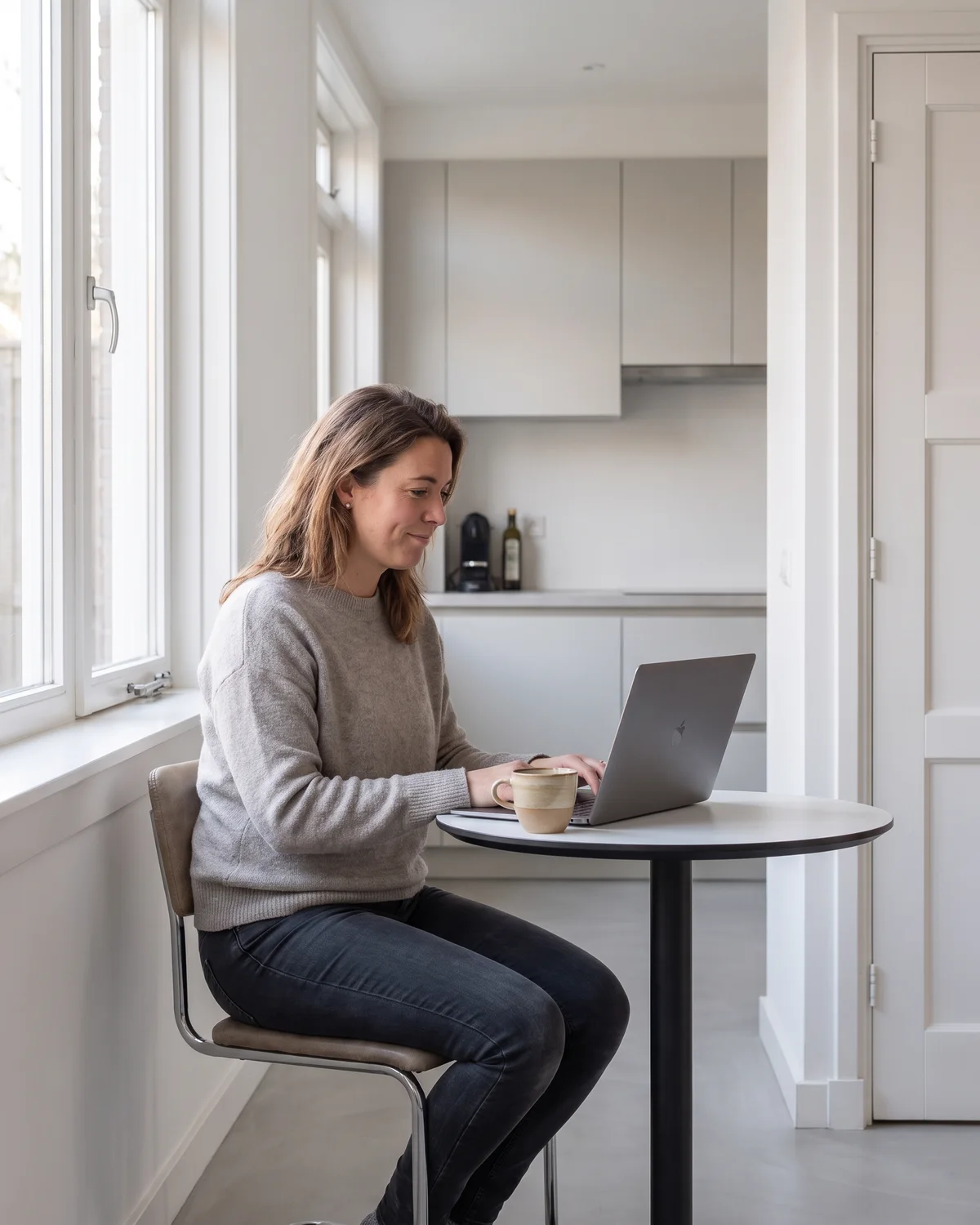 Een man werkt aan zijn laptop bij het raam