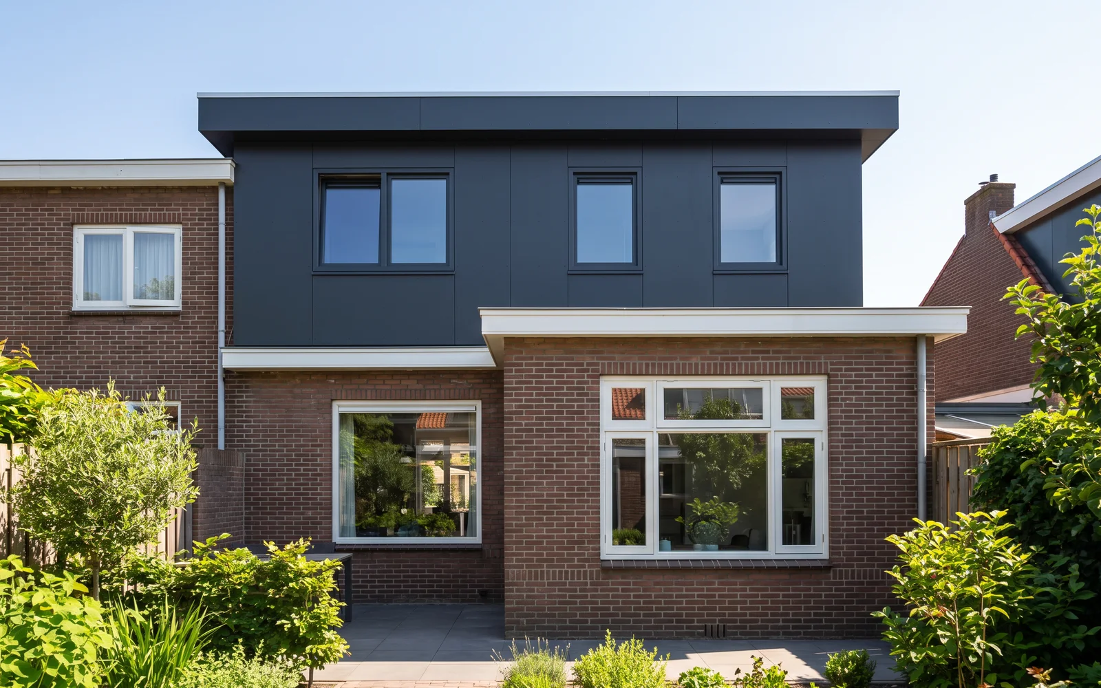 De achterkant van een rijwoning met een afgebouwde opbouw in antraciet op het platte dak