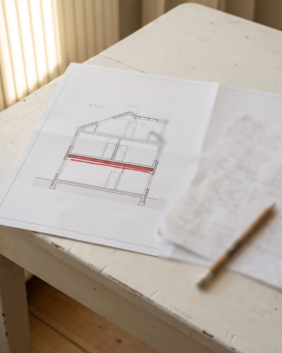 Een doorsnede van het huis met een stalen balk in rood, naast de berekening van de constructeur