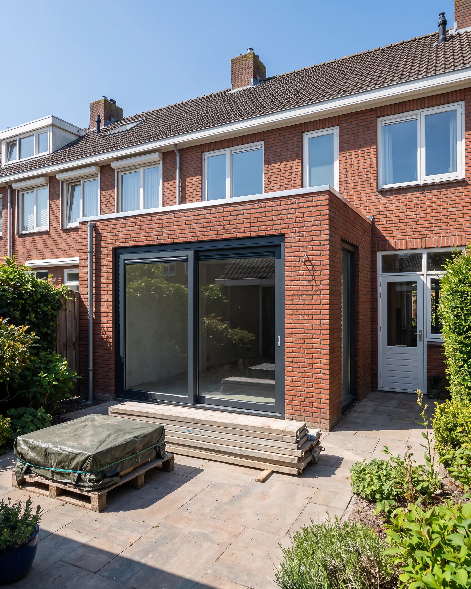 Een uitbouw waar een nieuwe schuifpui en dakrand zijn geplaatst, het herstel bijna klaar.