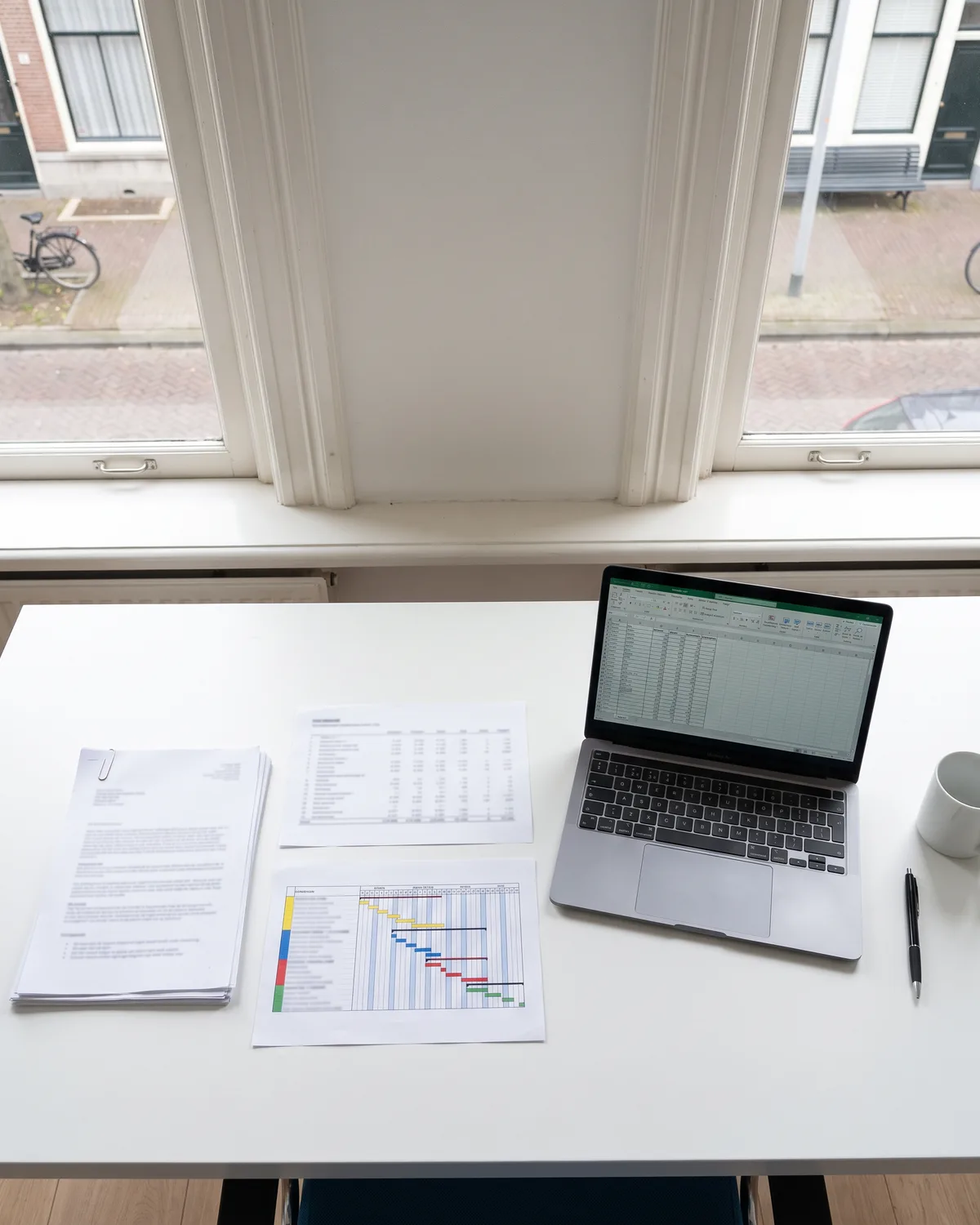 Uitgeprinte stukken en een laptop op een bureau