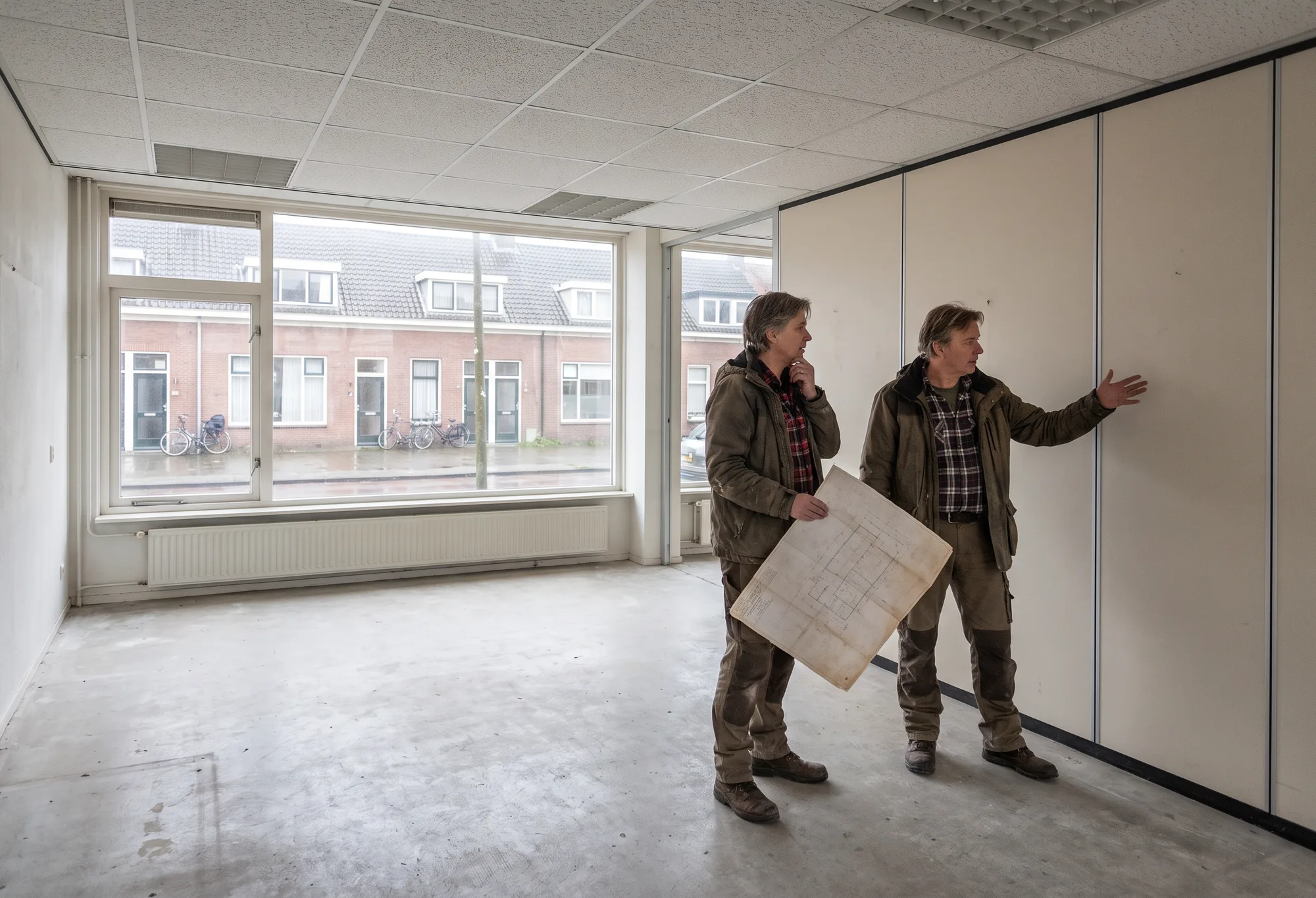Twee mensen lopen met een plattegrond door een leeg kantoorpand